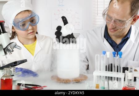 Ein junger Wissenschaftler führt Chemiekurse für ein Schulmädchen durch, das Experimente mit flüssigem Stickstoff und Trockeneis in einem chemischen Labor macht Stockfoto