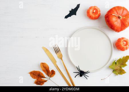 Halloween-Tischplatz mit dekorativen Kürbissen, Fledermaus, Spinne, Herbstblatt und orangener Kerze. Draufsicht, flach, Kopierbereich. Stockfoto