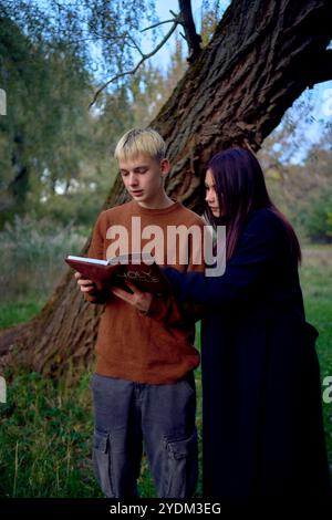 15-jähriges Teenager-Paar, das an einem kalten Herbstabend gemeinsam im Park die heilige Bibel liest Stockfoto