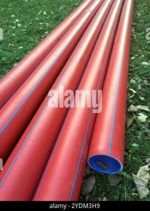 Die neuen fünf roten Rohre als Gehäuse für Elektrokabel sind für die Montage in der unterirdischen Nahaufnahme bereit Stockfoto