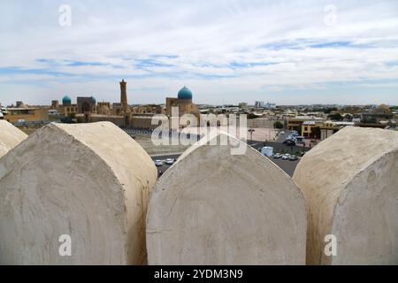 Blick auf Buchara mit Po-i-Kalan-Architekturkomplex und Kalyan-Minarett von der mittelalterlichen Archenfestung in Usbekistan. Selektiver Fokus auf die Festungsmauer Stockfoto