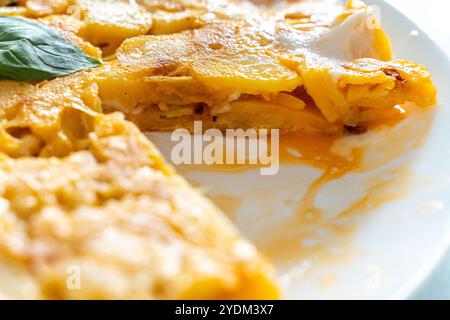 Spanisches Omelette oder Tortilla de patata, mit Kartoffeln und Zwiebeln, auf einem Teller, ein Stück abgeschnitten. Typisch spanische Küche. Hochwertige Fotos Stockfoto