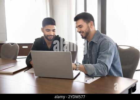 Zwei positive junge männliche Unternehmer aus dem Nahen Osten, die an einem Projekt arbeiten Stockfoto