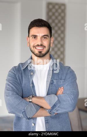 Glücklicher, selbstbewusster arabischer Geschäftsführer posiert mit überkreuzten Armen Stockfoto