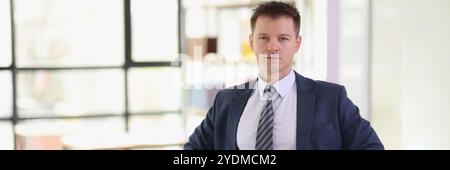 Ein seriöser Geschäftsmann hält sich im Amt an den Hüften fest Stockfoto