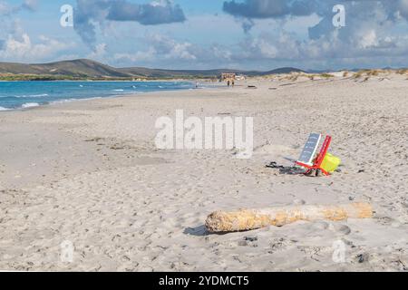 Zwei leere Stühle, eine weiße und eine rote, am breiten Sandstrand von Is Arenas Biancas, Sardinien, Italien Stockfoto