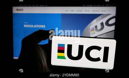 Person, die ein Smartphone mit dem Logo von Union Cycliste Internationale (UCI) auf dem Bildschirm vor der Website hält. Schwerpunkt auf dem Display des Telefons. Stockfoto