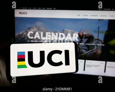 Person, die ein Mobiltelefon mit dem Logo von Union Cycliste Internationale (UCI) auf dem Bildschirm vor der Webseite hält. Schwerpunkt auf dem Display des Telefons. Stockfoto