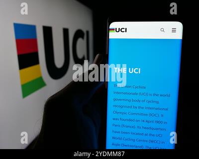 Person mit Smartphone und Website der Union Cycliste Internationale (UCI) auf dem Bildschirm vor dem Logo. Konzentrieren Sie sich auf die Mitte des Telefondisplays. Stockfoto