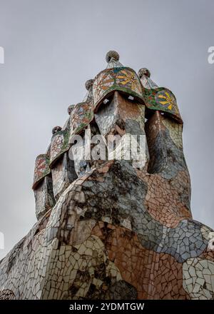 Barcelona, Spanien. Oktober 2024. Die Schornsteine von Casa Batll''' steigen bei leichtem Regen am Sonntagmorgen auf. Casa Batll''' ist ein Gebäude im Zentrum von Barcelona, Spanien, das von Antoni Gaud' entworfen wurde und als eines seiner Meisterwerke gilt. Wie alles, was Gaud entworfen hat, ist Casa Batll''' nur als Modernisme im weitesten Sinne erkennbar. Das Erdgeschoss hat unregelmäßige ovale Fenster und fließende Steinarbeiten. Es gibt nur wenige geradlinige Linien, und ein Großteil des faÂade ist mit einem bunten Mosaik aus gebrochenen Keramikfliesen verziert. Das Dach ist gewölbt und wurde mit der Rückseite einer Schleppe verglichen Stockfoto