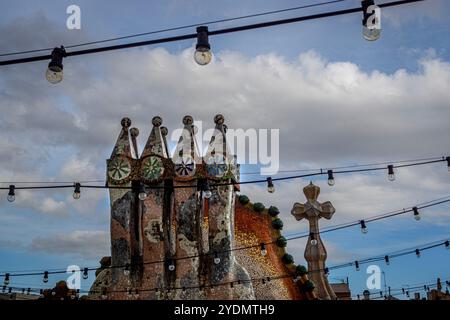 Barcelona, Spanien. Oktober 2024. Die Schornsteine von Casa Batll''' steigen bei leichtem Regen am Sonntagmorgen auf. Casa Batll''' ist ein Gebäude im Zentrum von Barcelona, Spanien, das von Antoni Gaud' entworfen wurde und als eines seiner Meisterwerke gilt. Wie alles, was Gaud entworfen hat, ist Casa Batll''' nur als Modernisme im weitesten Sinne erkennbar. Das Erdgeschoss hat unregelmäßige ovale Fenster und fließende Steinarbeiten. Es gibt nur wenige geradlinige Linien, und ein Großteil des faÂade ist mit einem bunten Mosaik aus gebrochenen Keramikfliesen verziert. Das Dach ist gewölbt und wurde mit der Rückseite einer Schleppe verglichen Stockfoto