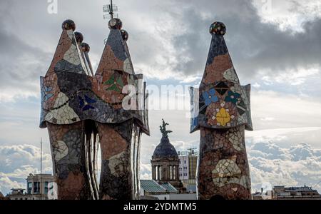 Barcelona, Spanien. Oktober 2024. Die Schornsteine von Casa Batll''' steigen bei leichtem Regen am Sonntagmorgen auf. Casa Batll''' ist ein Gebäude im Zentrum von Barcelona, Spanien, das von Antoni Gaud' entworfen wurde und als eines seiner Meisterwerke gilt. Wie alles, was Gaud entworfen hat, ist Casa Batll''' nur als Modernisme im weitesten Sinne erkennbar. Das Erdgeschoss hat unregelmäßige ovale Fenster und fließende Steinarbeiten. Es gibt nur wenige geradlinige Linien, und ein Großteil des faÂade ist mit einem bunten Mosaik aus gebrochenen Keramikfliesen verziert. Das Dach ist gewölbt und wurde mit der Rückseite einer Schleppe verglichen Stockfoto