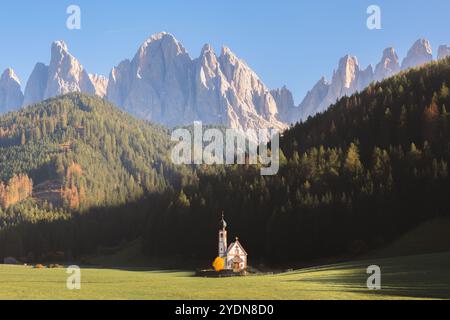 Die ikonische Kirche San Giovanni liegt im malerischen Val di Funes, eingerahmt von dichten Wäldern und den dramatischen Gipfeln der Dolomiten in Südtyro Stockfoto