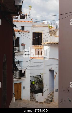 Ruhige, enge Straße in der Altstadt von Ibiza mit bezaubernden weißen Gebäuden mit traditionellen Balkonen und rustikaler mediterraner Atmosphäre Stockfoto