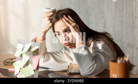 Freiberufliches Mädchen bläst Lippen und schaut auf Laptop Stockfoto