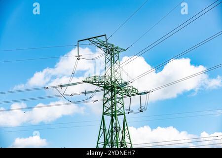 Power Tower und Kabel erstrecken sich elegant über einen hellen, klaren blauen Himmel mit weichen, flauschigen weißen Wolken Stockfoto