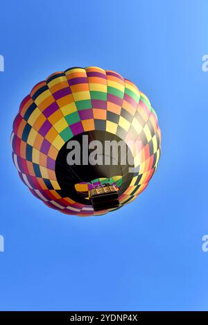 Der Heißluftballon erhebt sich über Collierville, Tennessee, in farbenfrohem, geometrischem Design. Blauer Himmel, toller Ballon während des Heißluftballonfestivals. Stockfoto