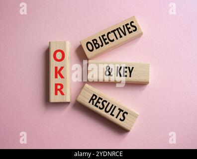 Symbol für OKR-Ziele und wichtige Ergebnisse. Holzblöcke mit den Worten OKR-Ziele und wichtige Ergebnisse. Schöner rosafarbener Hintergrund. Business- und OKR-Konzept. C Stockfoto