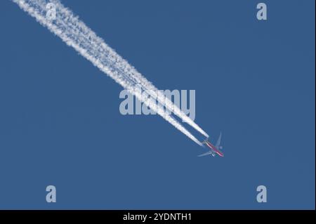 Transport airplane makes the very strong trace line of chemtrails on blue sky. Conspiracy theory. Stock Photo