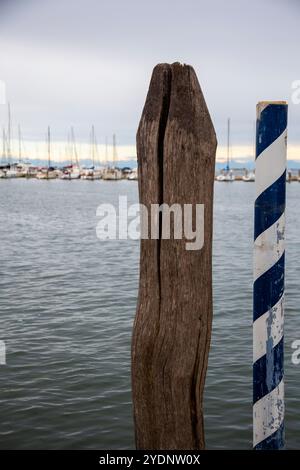 Zwei Pole aus verschiedenen Materialien, im Vordergrund, vor dem Hintergrund des Meeres und der vertäuten Boote, Chioggia Lagune, Venedig Gebiet, Italien Stockfoto