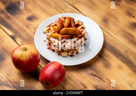 Belgische Waffeln mit Äpfeln in Weinsauce gedünstet auf einem weißen Teller auf hölzernem Hintergrund. Platz für Text. Hochwertige Fotos Stockfoto