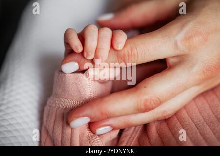 Nahaufnahme der Hand des Neugeborenen, die den Mutterfinger zärtlich berührt, herzerwärmender Moment der Verbindung und Liebe zwischen Mutter und Kind Stockfoto