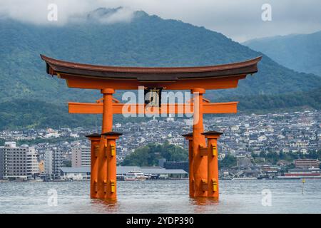 Hiroshima, Japan - 20. August 2024 : großes schwimmendes O-Torii-Tor am Itsukushima-Schrein bei Flut. Eine Fähre, die zum Pier der Miyajimaguchi Fähre ankommt Stockfoto