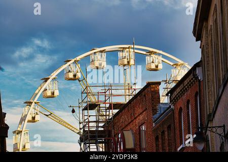 Im Hintergrund befindet sich ein teilweise gebautes Riesenrad mit sichtbaren Gerüsten und mehreren leeren Kabinen. Im Vordergrund, zwei Ziegel Stockfoto