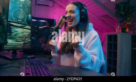 Fröhliche weiße Frau Gewinnerin Influencer Tippen Computer Spiel Spiel Internet süchtig E-Sport Gamer weibliche Bloggerin Lächeln gewinnen Match Sieg Mädchen Stockfoto