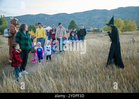 Lakewood, Colorado – Familien genießen den Haunted Trail vor Halloween im Bear Creek Lake Park. Ein Freiwilliger im Park, verkleidet als Hexe, führt auf eine tr Stockfoto