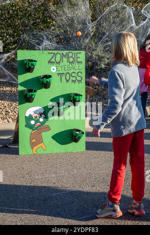 Lakewood, Colorado – Familien genießen den Haunted Trail vor Halloween im Bear Creek Lake Park. Ein Mädchen tritt beim Zombie-Augapfelwurf an. Stockfoto