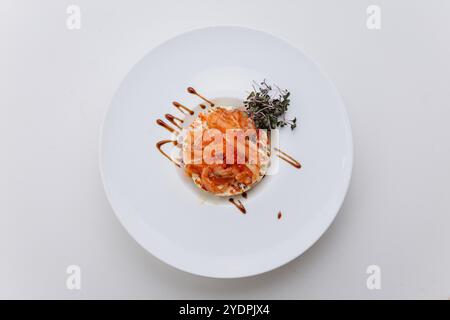 Gourmet-Lachs-Tartar mit rotem Kaviar, Kräutern und Sauce auf einem weißen Teller, raffinierte kulinarische Köstlichkeiten Stockfoto