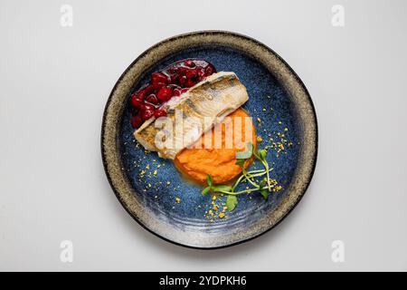 Gebackenes Fischfilet mit süßen Kartoffelpüree und Beerensauce, serviert mit Mikrogrün-Beilage Stockfoto