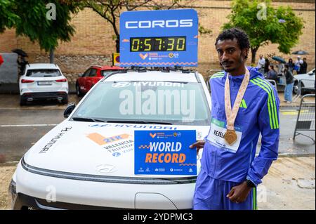 Der äthiopische Läufer Yomif Kejelcha posiert mit der Siegermedaille und der Stoppuhr des neuen Weltrekords beim Valencia Halbmarathon Stockfoto