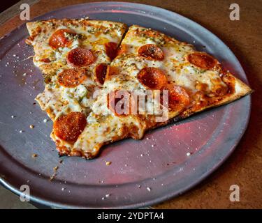 Zwei köstliche Stücke Peperoni Pizza auf einer Silberpfanne in einem Restaurant. Stockfoto