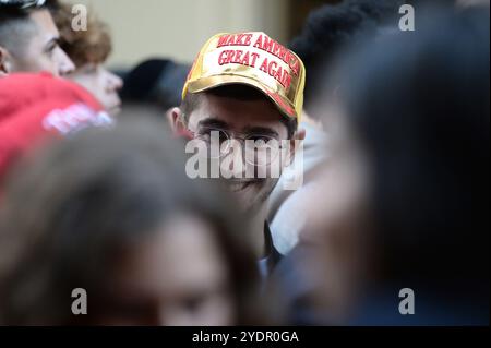 New York, USA. Oktober 2024. Ein Trump-Anhänger mit goldfarbenem MAGA-Hut wartet auf der 33rd Street, um den Madison Square Garden zu betreten, wo der ehemalige Präsident Donald Trump eine politische Kundgebung in New York, NY, 27. Oktober 2024 veranstaltet. (Foto: Anthony Behar/SIPA USA) Credit: SIPA USA/Alamy Live News Stockfoto