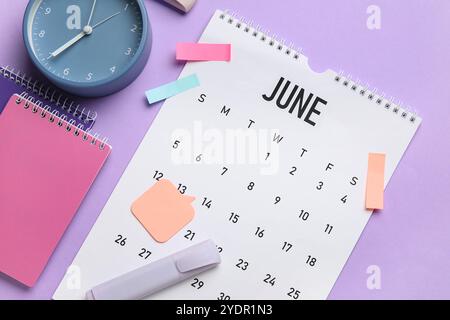 Kalender mit Wecker und Büropapier auf Fliederhintergrund Stockfoto