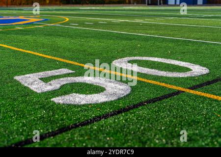 Kunstrasen Fußball 50-Yard-Linie, Blocknummer, in weiß zusammen mit schwarzer Lacrosse-Linie und gelber Fußball-Mittelfeldlinie Stockfoto