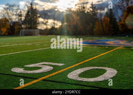 Kunstrasen Fußball 50-Yard-Linie, Blocknummer, in weiß zusammen mit schwarzer Lacrosse-Linie und gelber Fußball-Mittelfeldlinie Stockfoto