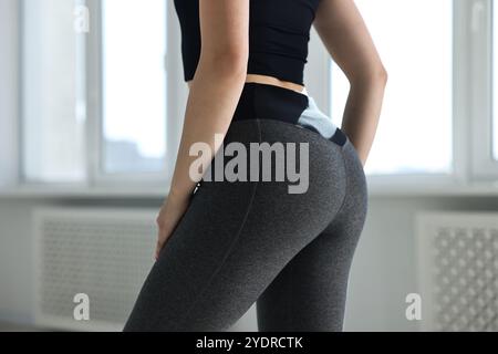 Frau trägt graue Sportleggings drinnen, Nahaufnahme Stockfoto