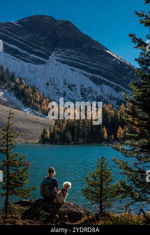 Eine Rucksacktouristerin genießt den atemberaubenden Blick auf den Chester Lake, mit dem schneebedeckten Mount Chester im Hintergrund und leuchtenden gelben Lärchen, die eine weitere Note verleihen Stockfoto