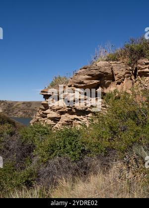 Sandsteinklippen am Missouri River in Great Falls, Montana, mit einheimischer Vegetation im Vordergrund. Stockfoto