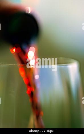 Rotwein wird aus einer Flasche in ein Glas gegossen Stockfoto