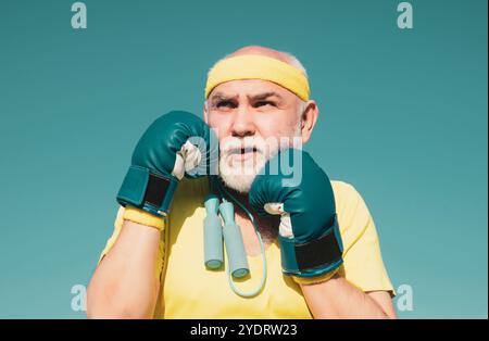Schöner älterer Mann, der Boxkick übt - Nahaufnahme Porträt. Gesunde Kämpfer Senior alten Mann Boxhandschuhe. Großvater beim Boxtraining Stockfoto