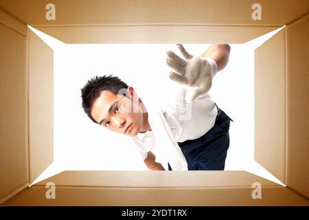 Arbeiter, der in einen Wellpappenbehälter schaut Stockfoto