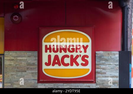 Das Schild für das Restaurant „Hungry Jack's“ wurde deutlich auf einem tiefroten Hintergrund mit einer Kombination aus gelber und weißer Färbung für das Logo gezeigt. Stockfoto