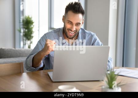 Fröhlich aufgeregter junger Unternehmer Mann, der Siegerhand macht Stockfoto
