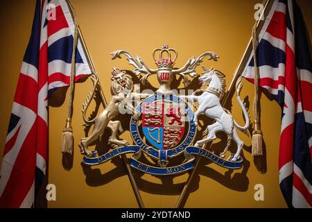 Dieses Bild zeigt das britische königliche Wappen, flankiert von zwei Union Jack Flaggen. Stockfoto