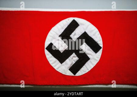 Dieses Bild zeigt eine Nazi-Flagge mit einem hellroten Hintergrund und einem weißen Kreis in der Mitte, der ein schwarzes Hakenkreuz enthält. Stockfoto