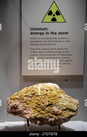 Perth Australien 18. März 2024 Eine Uranerzprobe, die in einer Museumsausstellung ausgestellt wird, begleitet von einem Informationsschild. Stockfoto